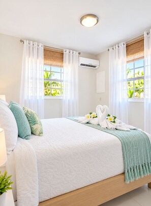 A neatly made bed with a white quilt, a teal throw blanket, and a swan-shaped towel arrangement. - Beija Flor Entire home in Oranjestad, Aruba (Opal)