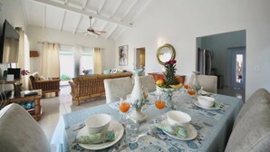 A dining area with a table set for four, a sofa, and a television in the background. - Beija Flor Entire home in Oranjestad, Aruba (Opal)