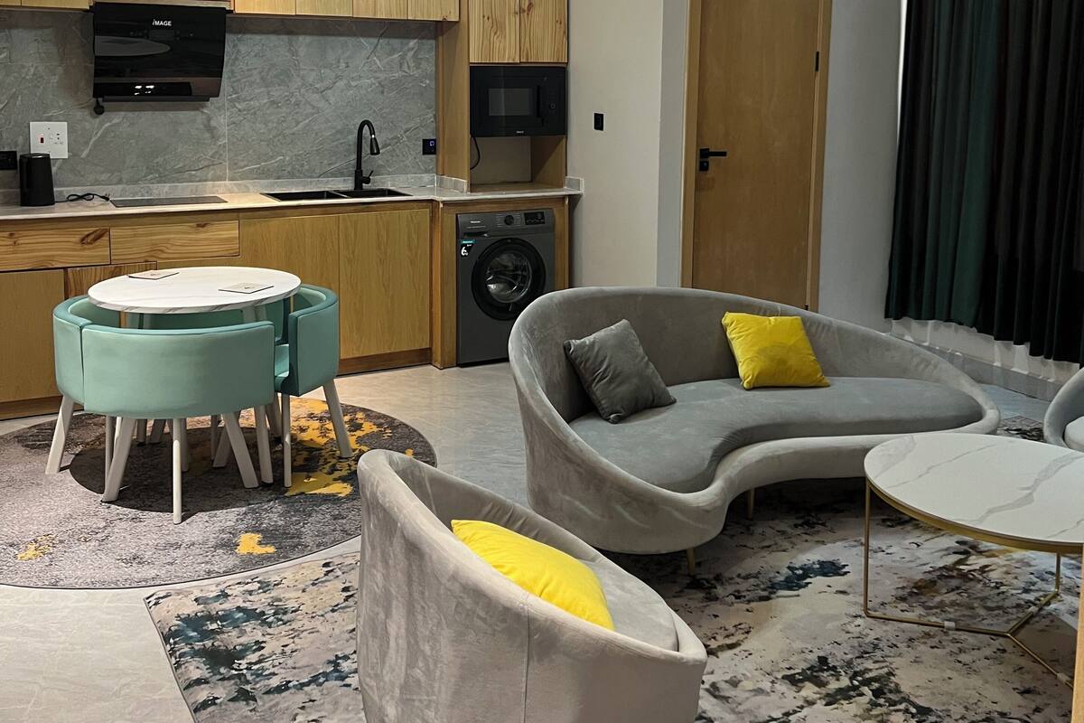 Una sala de estar moderna con un sofá, una mesa redonda de centro y un comedor con mesa y sillas.