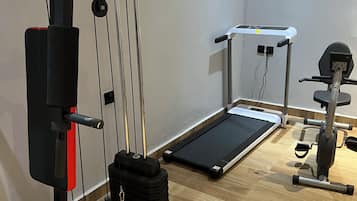 A gym with exercise equipment including a pull-up bar, a treadmill, and weight machines.