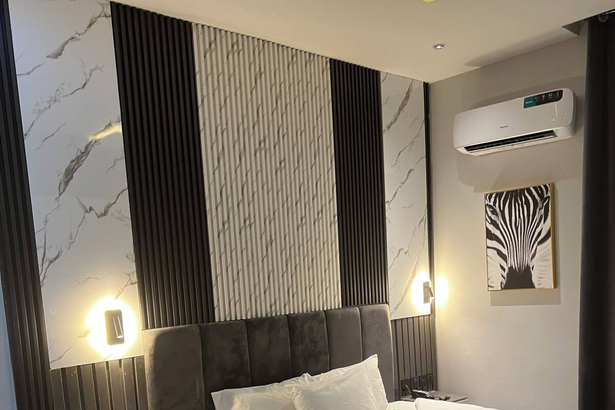 Una habitación de hotel moderna con una cama grande, una mesita de noche, un sofá y un equipo de aire acondicionado.