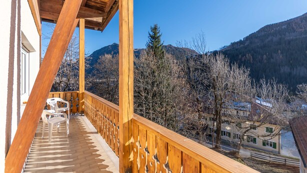 Een houten balkon met uitzicht op bergen en bomen.