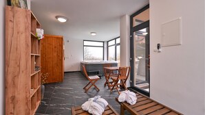 A modern bathroom with a wooden vanity, a hot tub, and a seating area with towels.