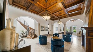 A spacious living area with a high wooden ceiling, a staircase, and blue upholstered furniture. - 5BR Luxury Villa • Games & Golf • Near Disney (Reunion)