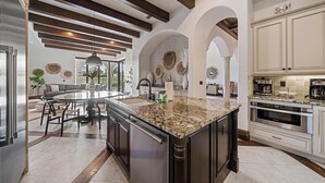 A spacious kitchen with a large island, modern appliances, and a view of the outdoors. - 5BR Luxury Villa • Games & Golf • Near Disney (Reunion)