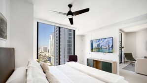 A modern hotel room with a large bed, a flat-screen TV, a ceiling fan, and a city view through the window. - 601 RESIDENCES URBAN 1BR UNIT #2613 (Miami)