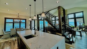 Una cocina amplia con una isla grande, luces colgantes y vistas al exterior.