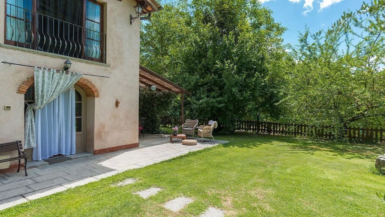 Ein Haus mit gepflasterter Terrasse, Gartenmöbeln und einem gepflegten Rasen.