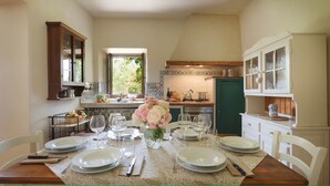 A dining area with a table set for four, a vase with flowers, and a kitchen in the background. - Casa al Fiume - Villa with private pool (Terranuova Bracciolini)