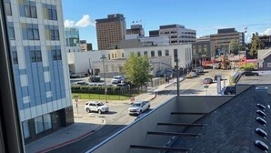 A view of a parking lot with several cars, a building with a modern design, and a clear blue sky. - Artsy 1 Bedroom Condo with the Views to the Inlet! (Anchorage)