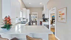 Une cuisine moderne avec des meubles blancs, un îlot central et un coin repas avec des chaises.