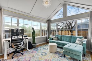 A sunlit room with a desk, chair, sofa, and a potted plant. - Modern 3BD house in walkable Ballard, family and dog-friendly, A/C, fenced yard (Seattle)