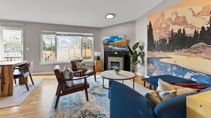 Un salon moderne avec une cheminée, un grand tableau et un coin repas doté de meubles en bois.
