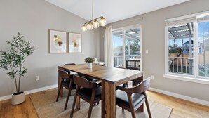 Un coin repas avec une table en bois, des chaises, une plante en pot et des œuvres d’art encadrées accrochées au mur.