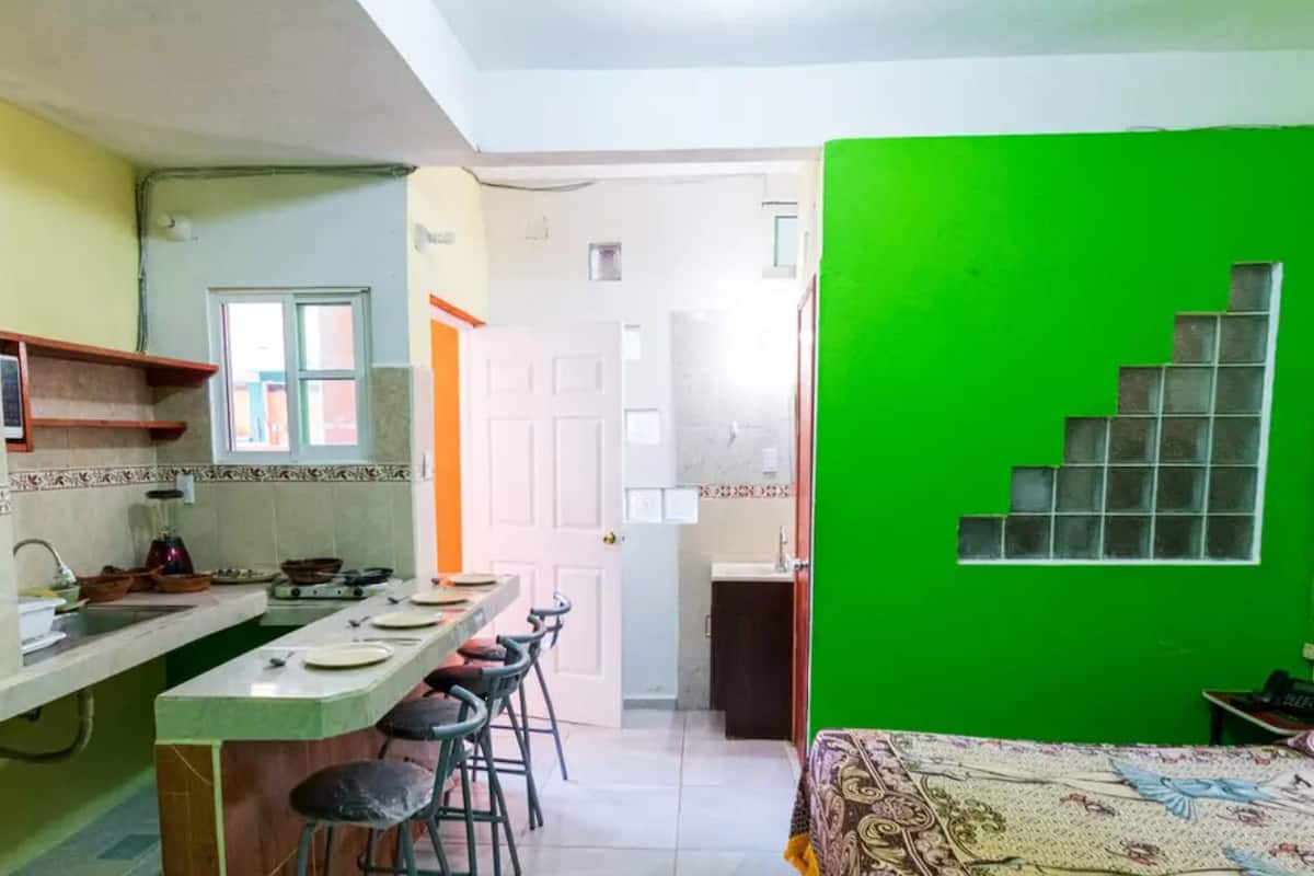 A compact kitchen with a dining area, a staircase, and a bed.