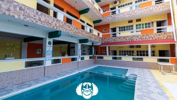 Un hôtel à plusieurs étages doté d’une piscine centrale dans une cour intérieure, de balcons et d’une enseigne indiquant le nom et l’emplacement de l’hôtel.