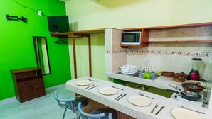 Une cuisine compacte avec un mur vert, un meuble en bois, un four à micro-ondes et un évier.