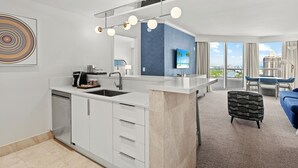 Moderni keittiö, jossa on keskeinen saareke, ruokailutila, josta on kaunis näköala, ja olohuone, jossa on sininen sohva.