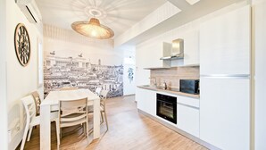 Una cuina moderna amb armaris blancs, taula de dinar de fusta i cadire.