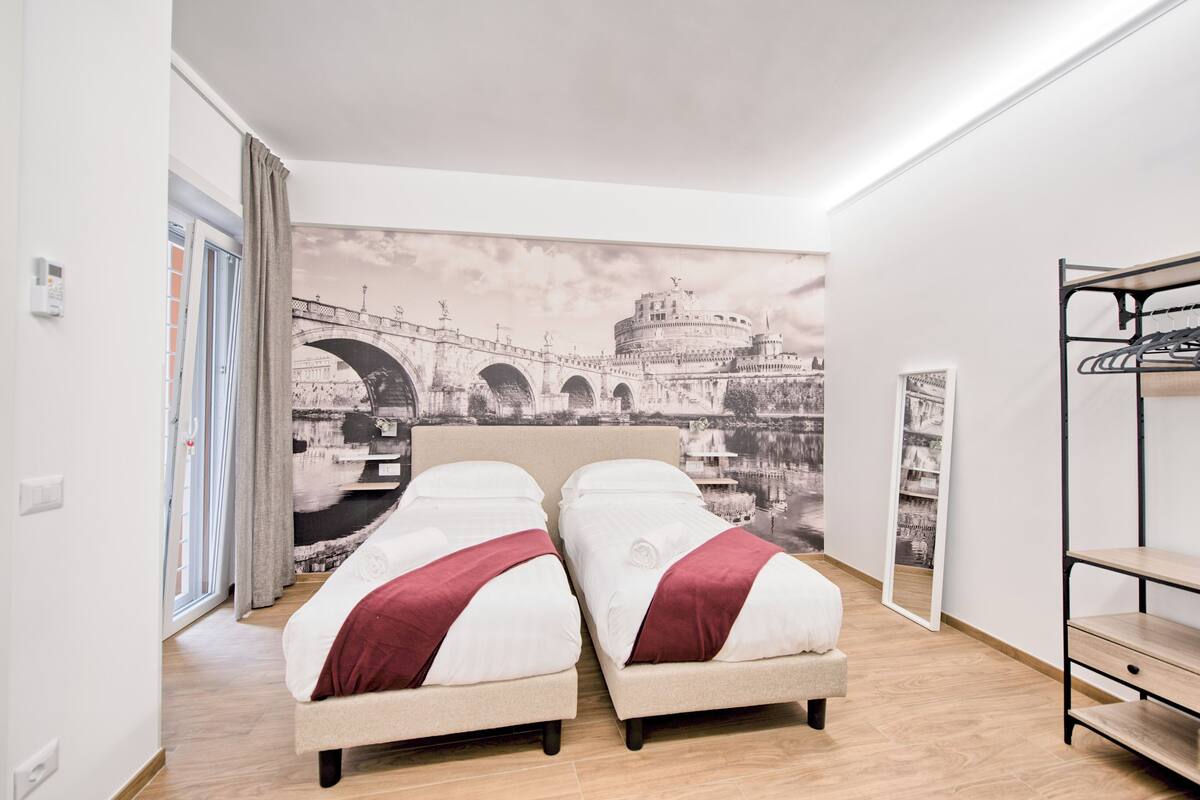 Ein Zimmer mit zwei Betten, einer großen Brücken-Mural, einem Kleiderschrank und einem Spiegel.