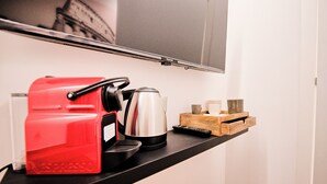 Un taulell de cuina amb una màquina d'espresso vermella, una cafetera i un comandament a distància.