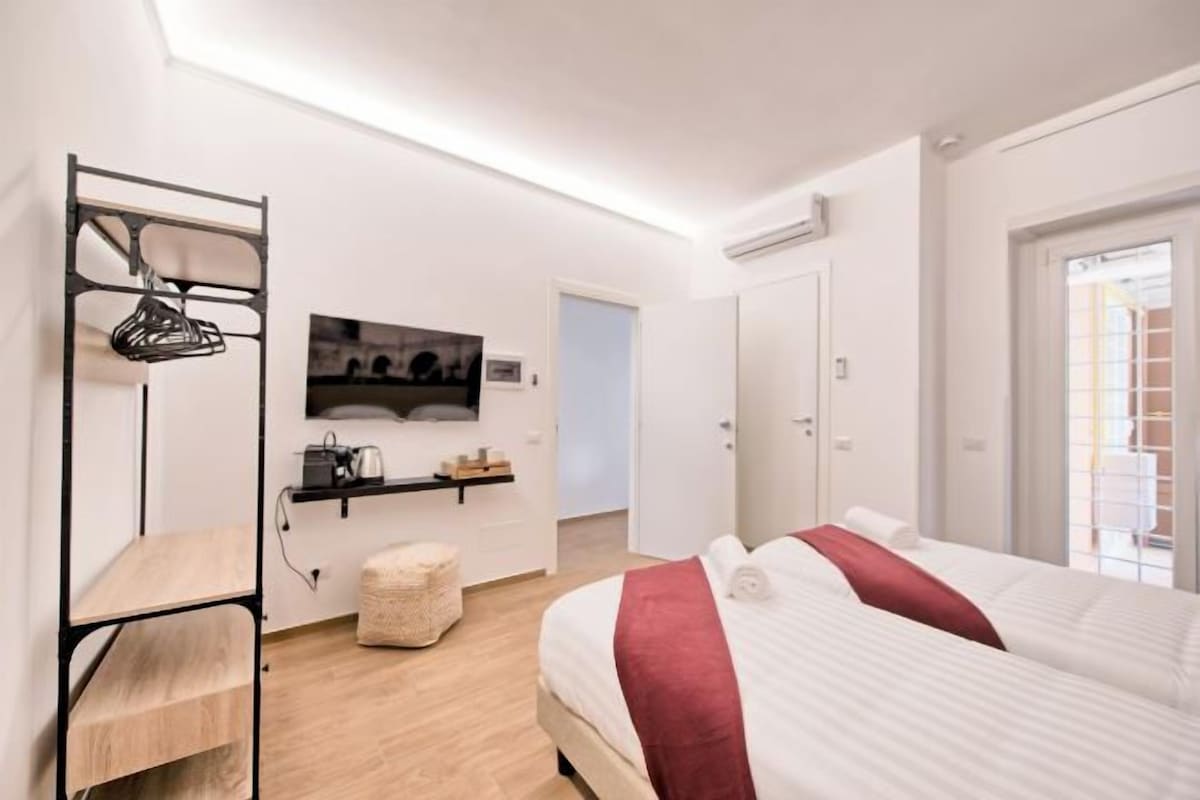 A modern hotel room with a bed, a desk, and a TV.