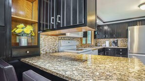 A modern kitchen with granite countertops, stainless steel appliances, and dark cabinetry. - Lovely Lakehouse by Grand Traverse Bay. Pet Friendly! (Traverse City)