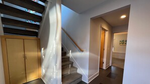 A modern interior with a staircase, a wooden door, and a hallway leading to another room. - SUNSET PLACE (Grand Haven)