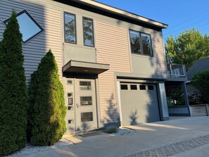 A two-story house with a garage, a covered entryway, and a small porch. - SUNSET PLACE (Grand Haven)