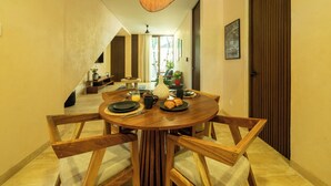 A dining area with a round wooden table, chairs, and a hanging light fixture. - Jungle & Relax: Private Pool- Garden Wifi  (Tulum)