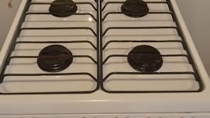 Una estufa blanca con cuatro hornillas y cuatro perillas, con la etiqueta 'mabe' y 'horno'.