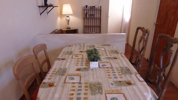 Una mesa de comedor con mantel estampado, rodeada de sillas de madera.