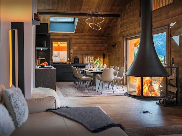 A modern interior with a dining area, kitchen, and a fireplace.