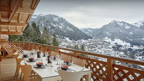 A dining area with a table set for four, overlooking a snow-covered mountain town.
