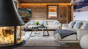 A cozy living room with a fireplace, sofas, and a large painting on the wall.