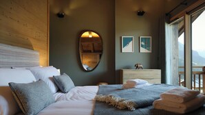 Ein Schlafzimmer mit Bett, Kissen, Kommode, Spiegel und Bildern an der Wand.