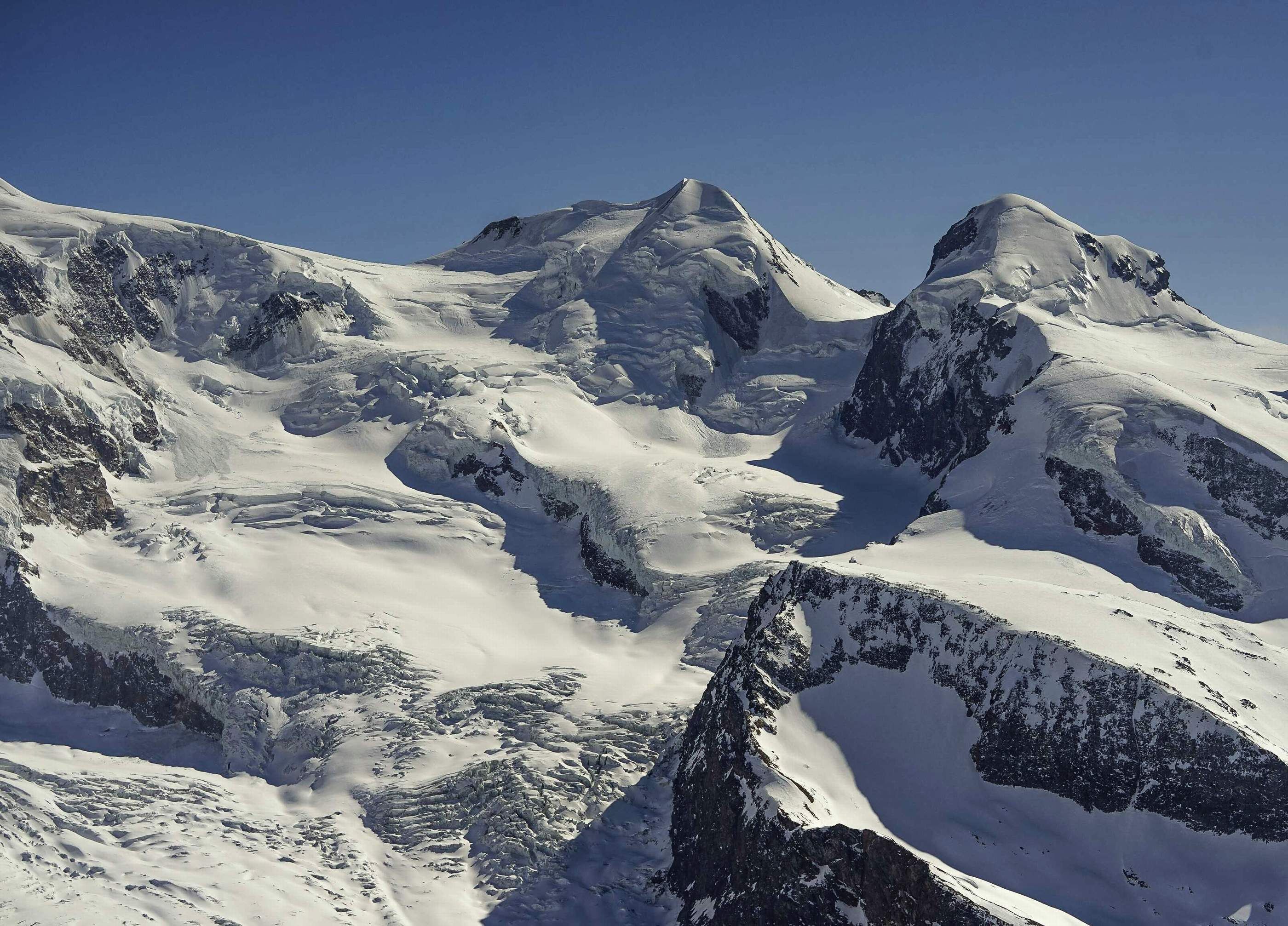Paisaje montañoso cubierto de nieve con terreno accidentado y picos escarpados.