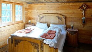A wooden bedroom with a large bed, two bedside tables, and a wooden headboard. - Authentic, beautiful chalet, from 1679. Refurbished. At an altitude of 1,800 m. (Törbel)