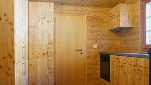 A kitchen with wooden cabinets, a refrigerator, an oven, and a window. - Authentic, beautiful chalet, from 1679. Refurbished. At an altitude of 1,800 m. (Törbel)
