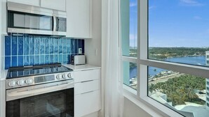 A modern kitchen with a gas stove, microwave, and toaster, large windows with a city view.