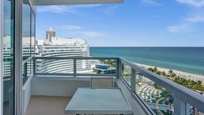 A balcony with a clear view of the ocean and a resort area.