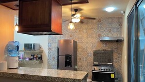 A kitchen with a built-in oven, a refrigerator, a microwave, and a water dispenser.