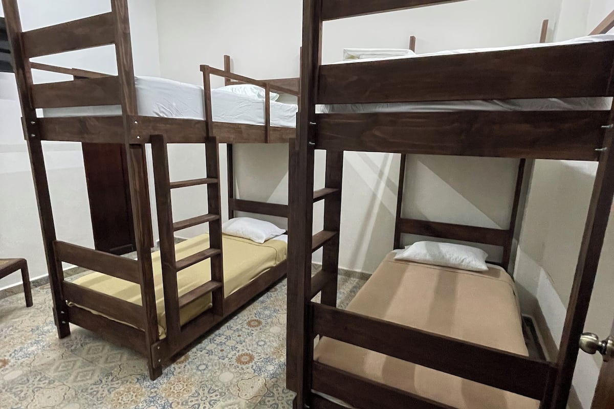 Une chambre avec des lits superposés, un ventilateur de plafond et des carreaux de sol à motifs.