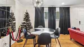 A modern living room with a round table, black chairs, a red sofa, and a Christmas tree.