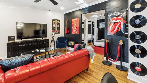 A modern living room with a red leather sofa, a black TV, and a ceiling fan.
