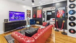A modern living room with a red leather sofa, a TV, and a ceiling fan.