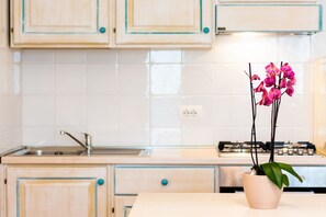 A kitchen with wooden cabinets, a sink, and a gas stove.