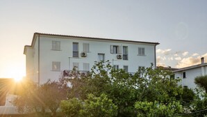 Un edifici de diverses plantes amb teulada plana i nombroses finestres, envoltat de vegetació.