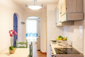 Cocina con armarios blancos, encimera de madera y cesta de frutas.