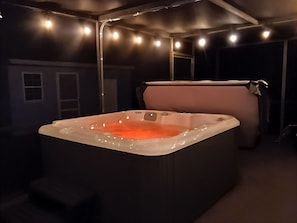 Een spa-ruimte met een bubbelbad, gedimd licht en een donkere sfeer.